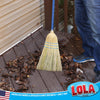 LOLA corn broom sweeping dry leaves from an outdoor wooden deck.