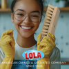 Smiling woman in yellow gloves holding Lola hand scrub brush in kitchen, American owned and operated since 1969