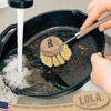 Pot and pan brush cleaning a greasy pan at the kitchen sink for dishwashing cookware cleanup