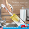 Hand using Lola glass brush to clean inside a tall glass at the sink; text: fits most glasses and mugs, family business since 1969