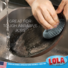 Hands using Lola wire mesh scourer to scrub a burnt cast iron pan under running water; text: Tough Abrasive Jobs, American owned since 1969