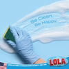Blue-gloved hand using Lola Scour-N-Sponge to wipe soapy surface. Text: Be Clean. Be Happy. American owned since 1969.