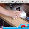 Lola white melamine eraser pad works on many surfaces, shown cleaning a kitchen countertop near a stainless steel sink