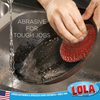 Gloved hand holding flat copper coated knitted wire mesh scourer scrubbing stainless steel bowl at sink, heavy duty