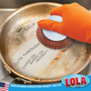 Orange-gloved hand grips Lola copper mesh scourer with white knob handle to scrub caked-on, baked-on messes from soiled stainless steel pan