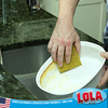 Gold Wonder Scourer scrubber pad scrubbing baked-on food from a white baking dish for kitchen cleaning