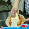 Hand using yellow Lola nylon net scrub pad to scrub a casserole dish at the kitchen sink; American owned family business since 1969